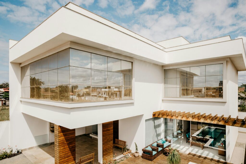 Stylish contemporary house exterior with large windows and wooden details under a blue sky.